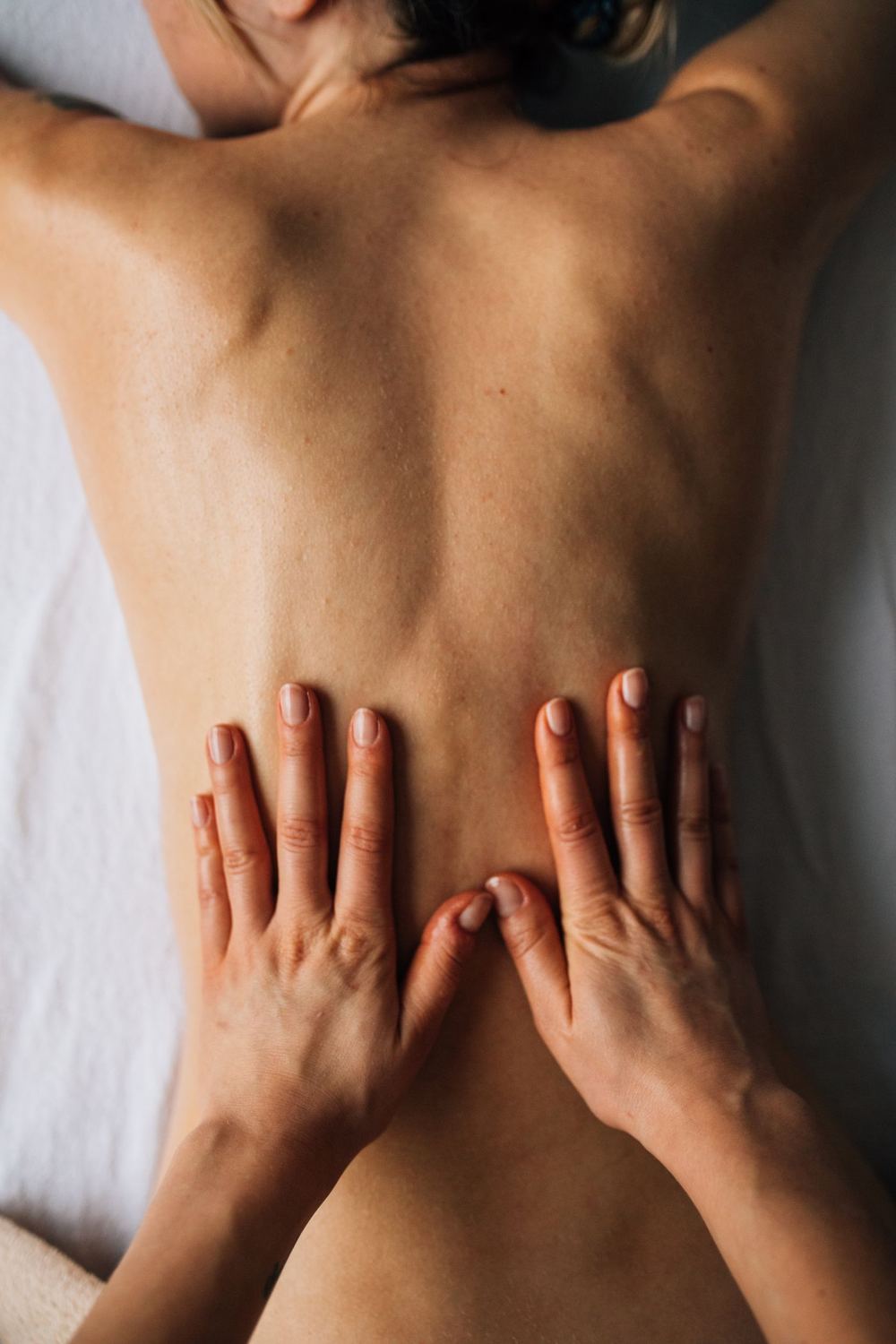 A massage therapist working across a client's back during a restorative treatment