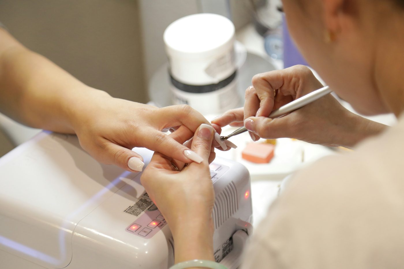 A nail technician applying gel polish during a manicure